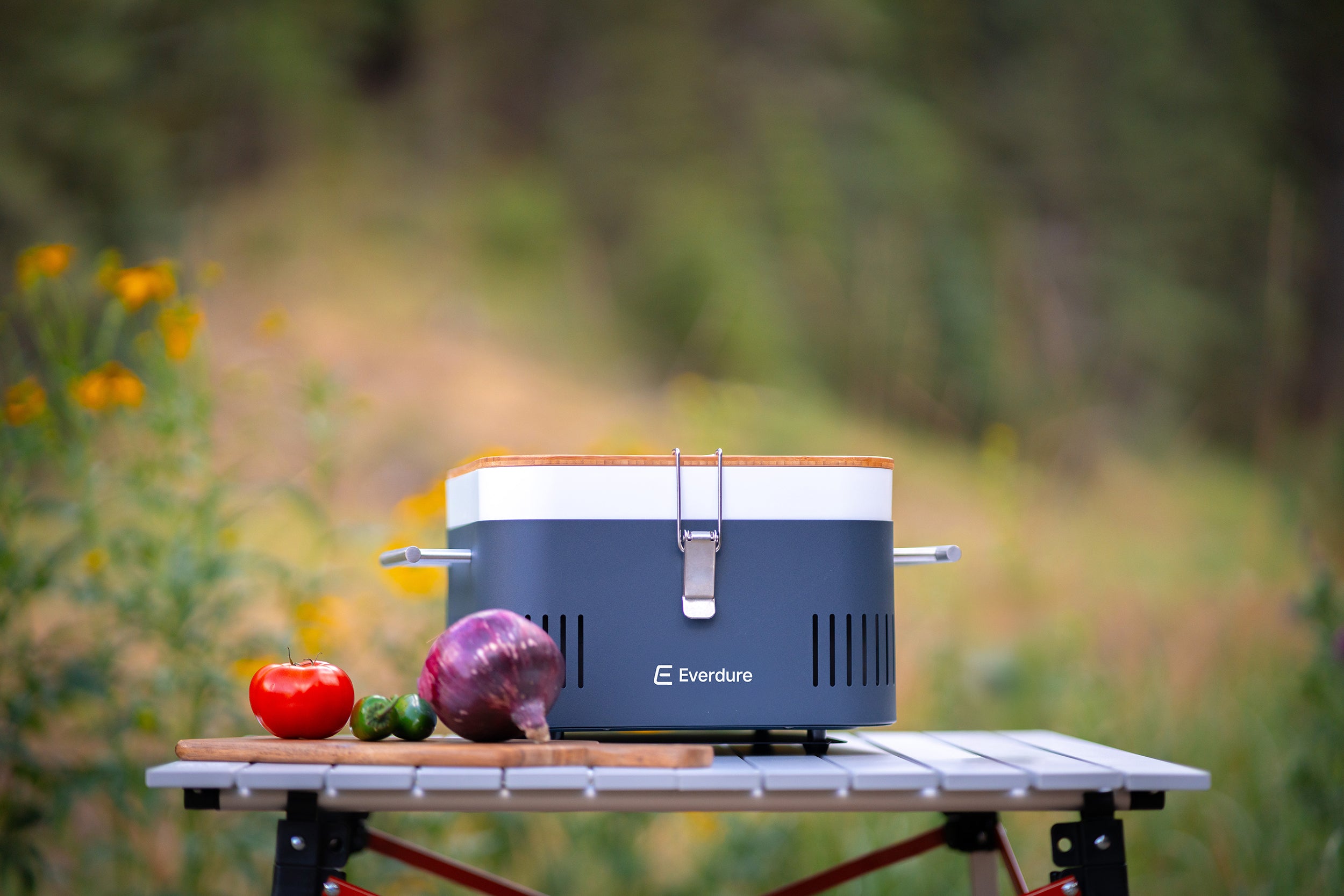 Portable grill on a table with vegetables in an outdoor setting